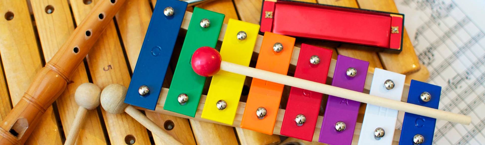 A photo of compiled musical instruments for children including a red harmonica, a woooden recoder and a coloful xylophone like the ones used at the the music circle classes for kids in Zurich and Staefa, Switzerland.  