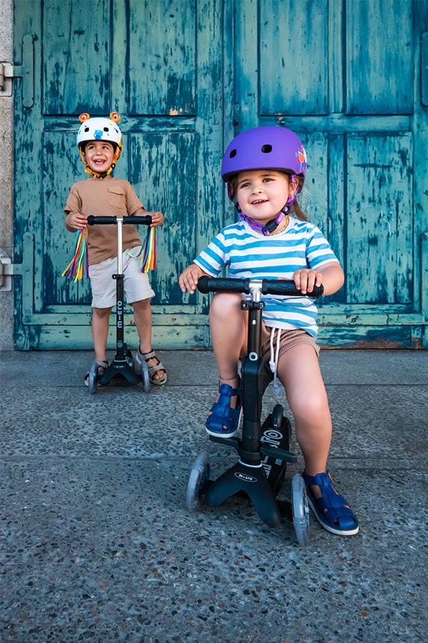 Mini Micro 3-in-1 ECO – Kleinkind sitzt/rollt auf 3-rad Scooter; zwei Kinder mit Helm zeigen Sitz- und Scooter-Modus.