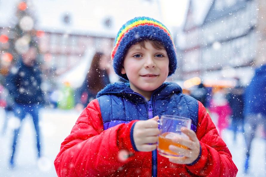 A young boy drinking hot punch at the ice rink in Lachen, by Lake Zurich