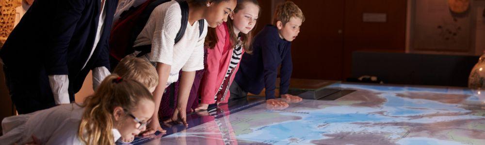 At the Nature Museum in Luzern, a group of teens that are part of a school group are leaning over natural artefacts on display.