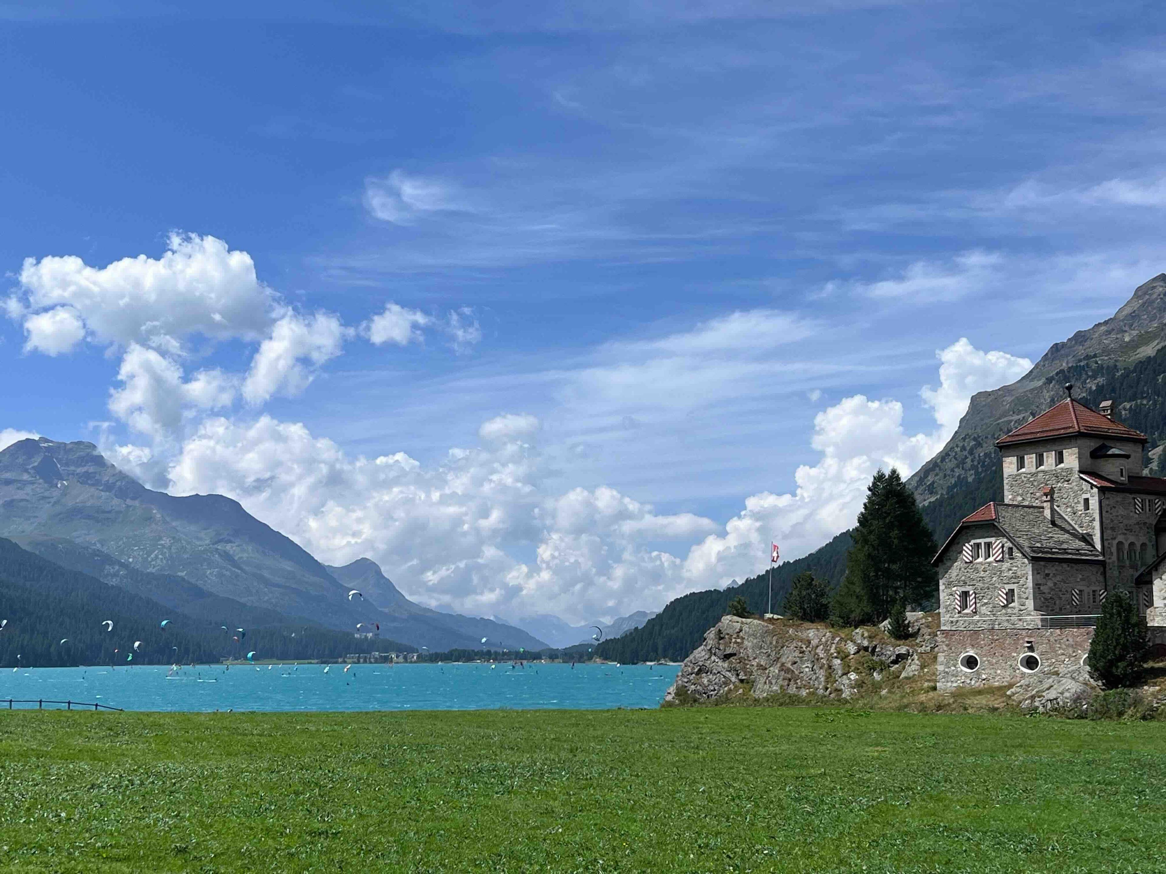 A view of the Silvaplana lake in Engadin showing kite-surfers in the distance, for the outdoor activities with kids in Switzerland blog post