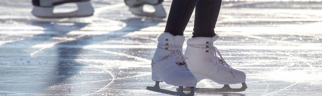 A close-up of a girl's white ice-skates on the ice outdoors on a sunny day on one of the many ice-rinks around Zurich, Switzerland.  