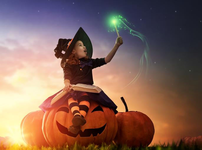 girl in witch costume reading book halloween pumpkin 