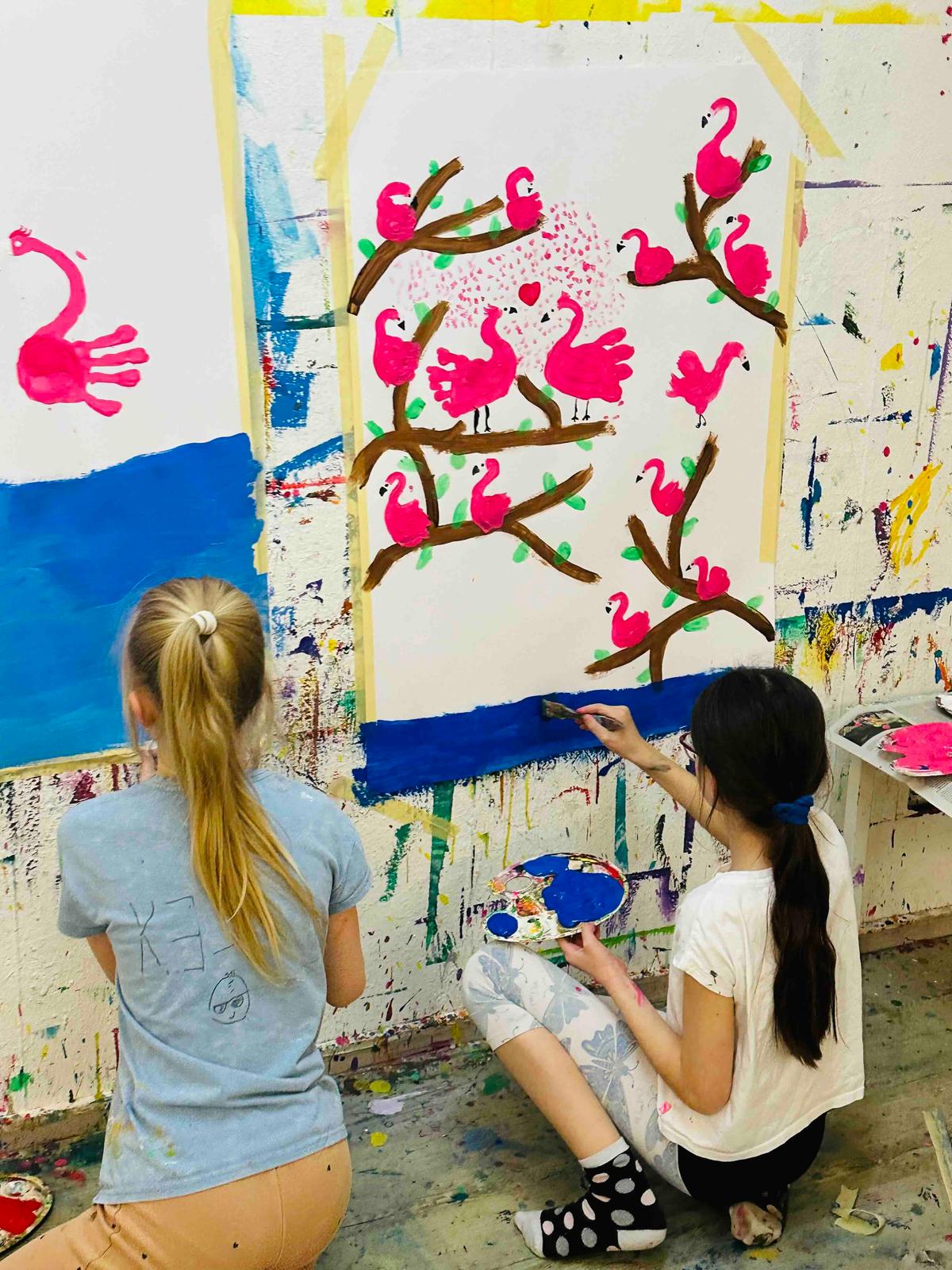 Two girls painting their canva on the wall with hand pressed flamingo images at the Storycraft studio in Rüschlikon, Zurich.  