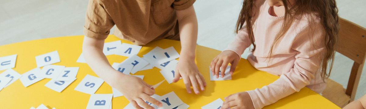 Two primary school children are sorting out letters of the alphabet on a yellow table during an English class at AtoZ English in Switzerland.  