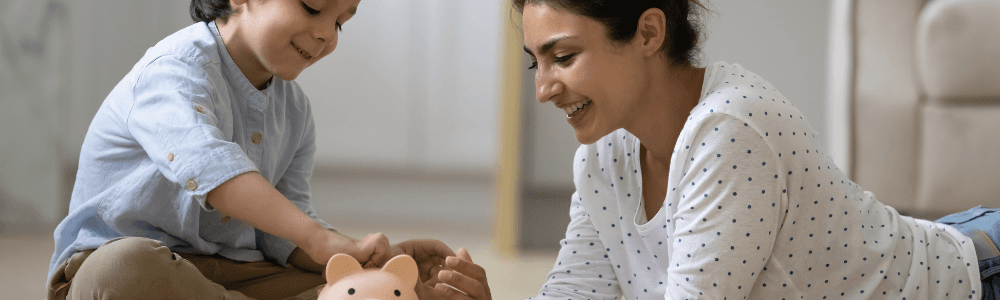 Mother and toddler are learning about money and putting savings aside in a piggy bank