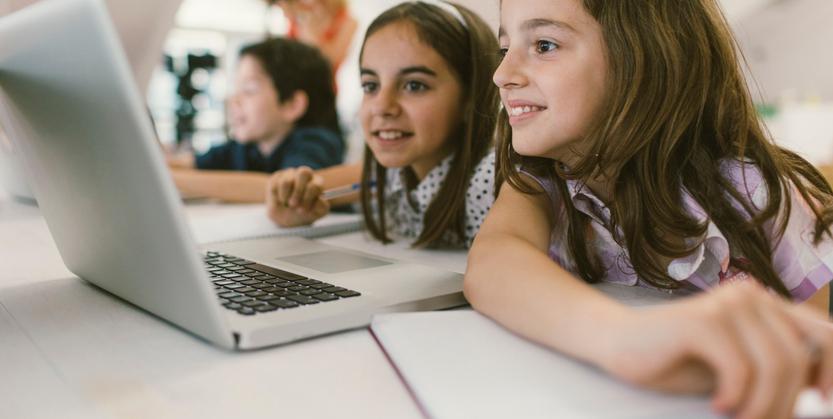 A group of girls and boy are working on an online project on their laptop