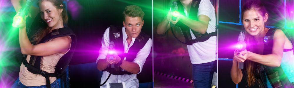 A group of teenagers, boys and girls posing in the laser tag center in Schwerzenbach Switzerland.  They are holding their guns inside a dark room with colorful neon laser lights.  