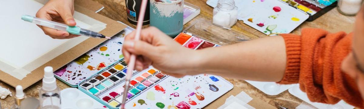 An image of a table covered in water paints, and drawings with paintbrushes on paper during a workshop of young children at the Museum of Greek Children's Art in Athens, Greece.