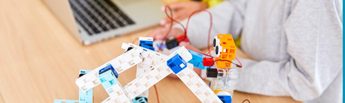 Children engaging with colorful, interactive robots in a playful, educational setting focused on STEM activities and creative exploration.