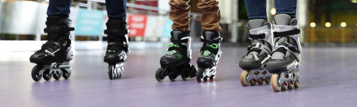 Children roller skating on the indoor disco-themed rink at SportsPark, illuminated by colorful lights.