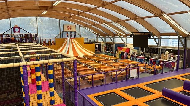 A colorful photo of the giant trampoline spaced roofed under a windowed dome at the Swiss Mega Park near Basel. A place for sports, leisure and family fun indoors.  
