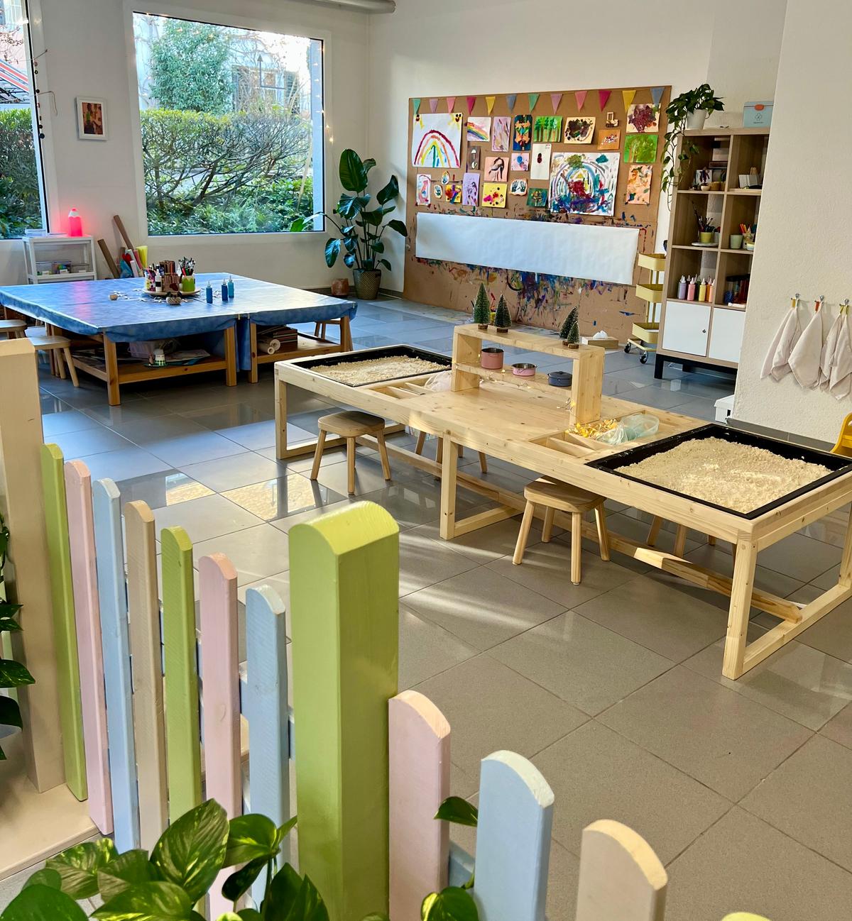 An image of the workshop area of Tiny Hands Creations, it is colorful and bright with light coming through large windows.