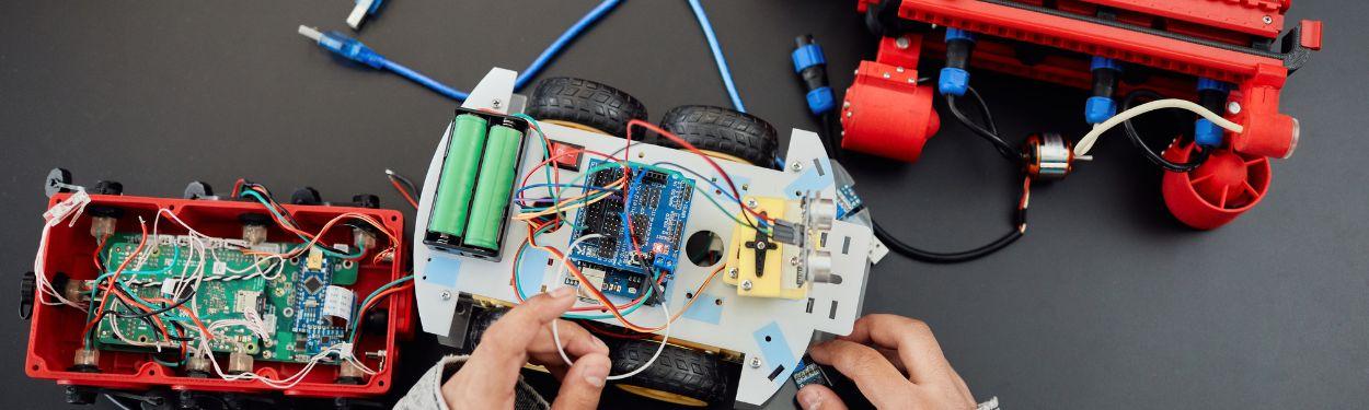 A robotic car being assembled by kids at summer camps in Switzerland, full of wires and batteries connecting together.  