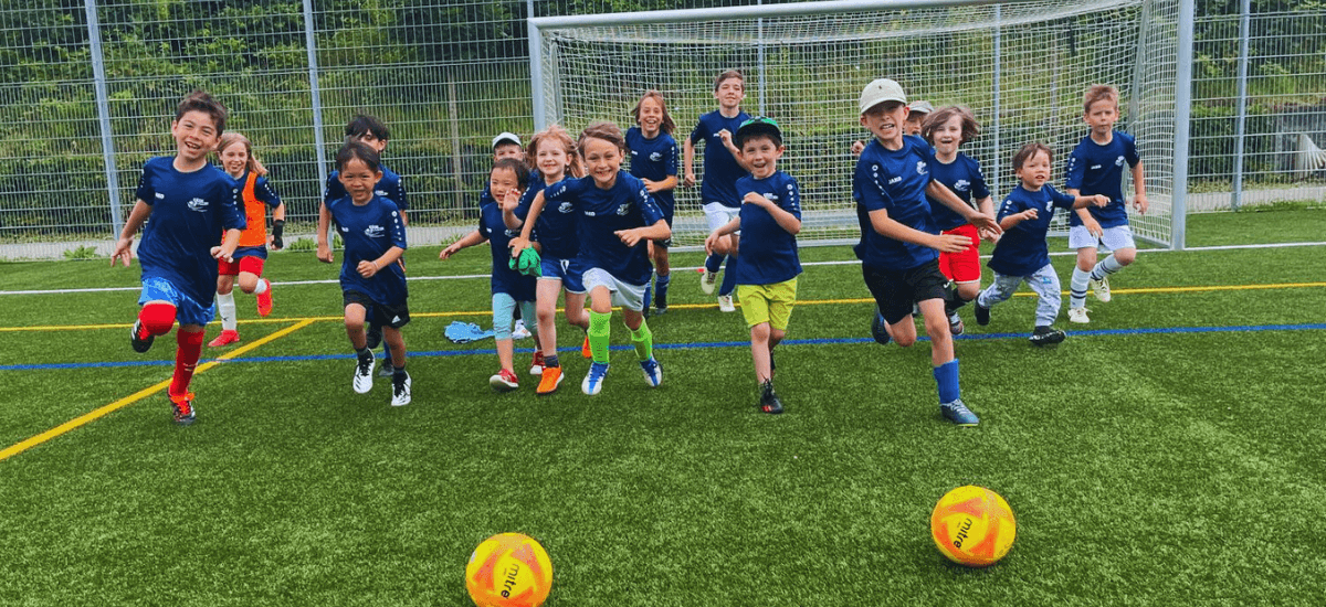 Kids at Intersoccer after-school classes in Zug are running after the ball during a game