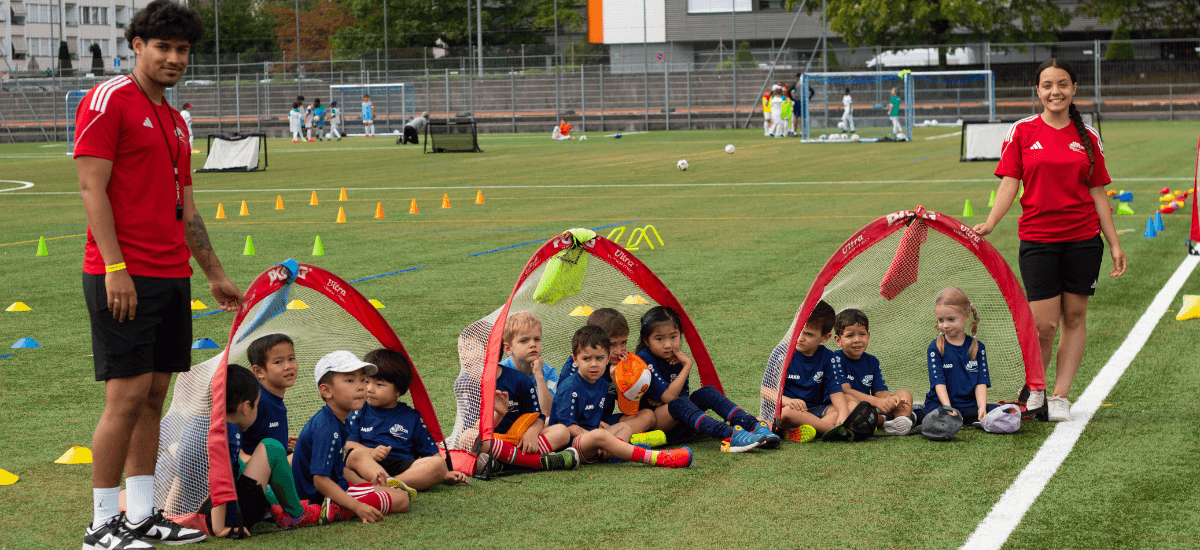 Kids at Intersoccer after-school classes in Zurich are resting on the field after their training.