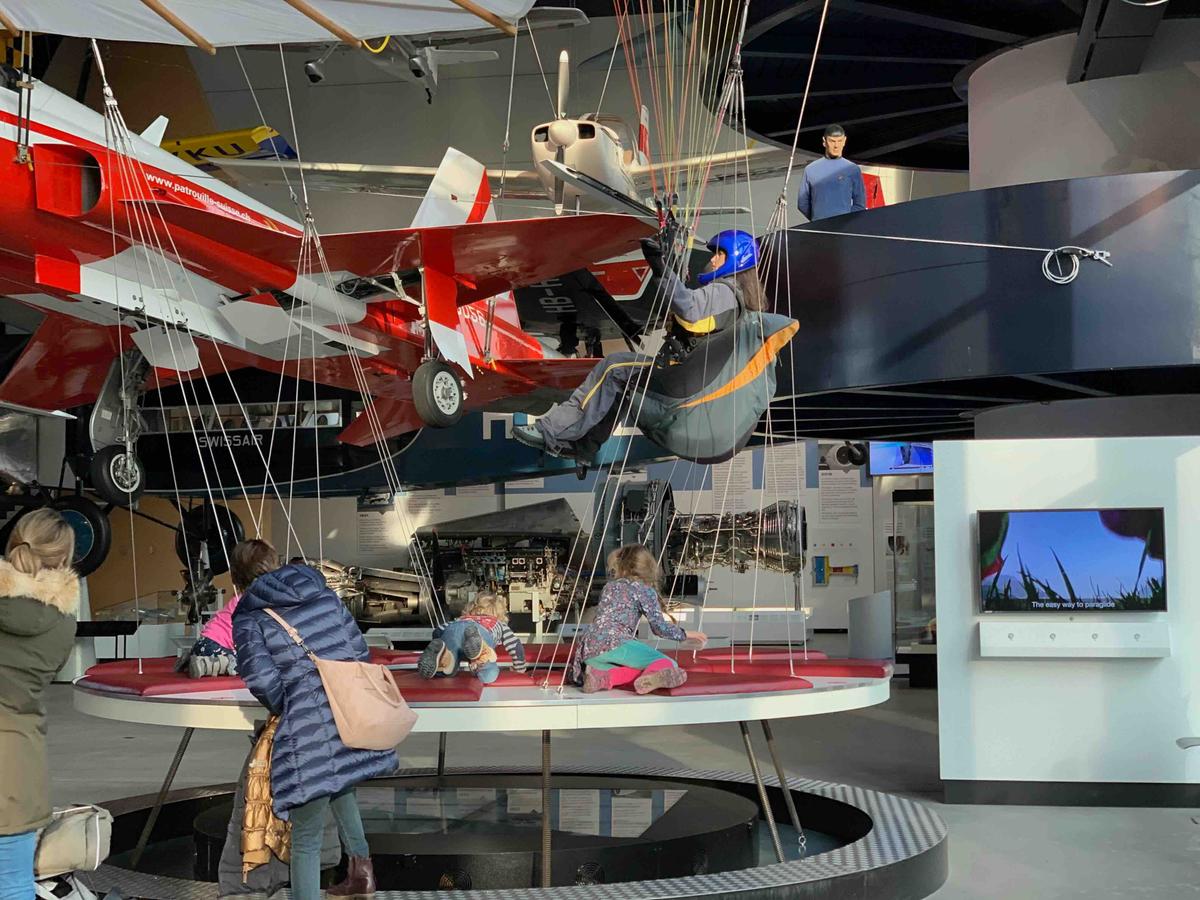 A model figure landing a parachute among different types of planes and landing devices on display at the Luzern Transport Museum, Switzerland.