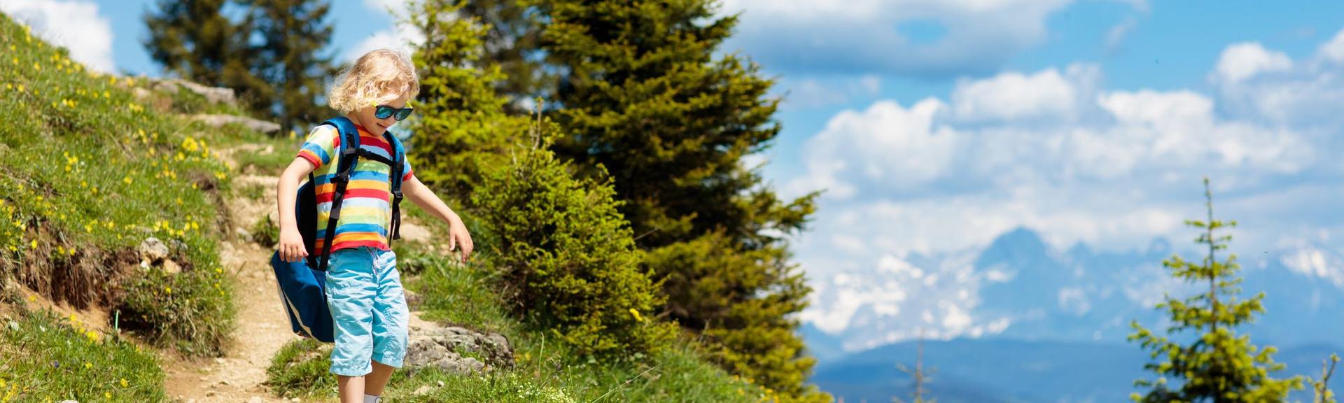 A blond young buy walking down a mountain trail on Mount Pilatus in Canton Luzern, during summer time.  