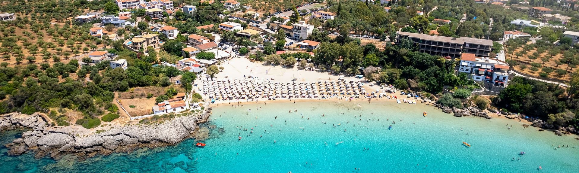 Πανοραμική θέα της παραλίας Καλόγριας με γαλαζοπράσινα νερά, αμμώδη ακτογραμμή και φυσική βλάστηση.