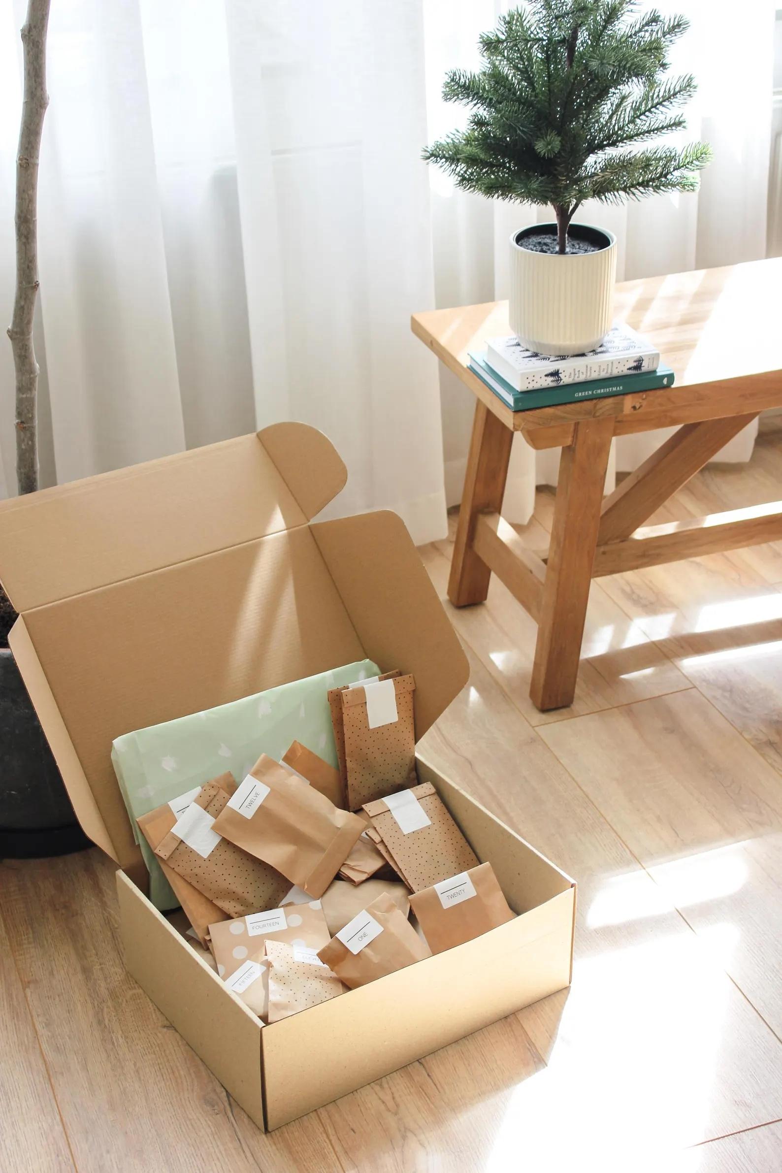 Offene Box mit 24 nummerierten Päckli in Naturpapier – minimalistischer Adventskalender zum Selberbefüllen, gemütlich inszeniert.