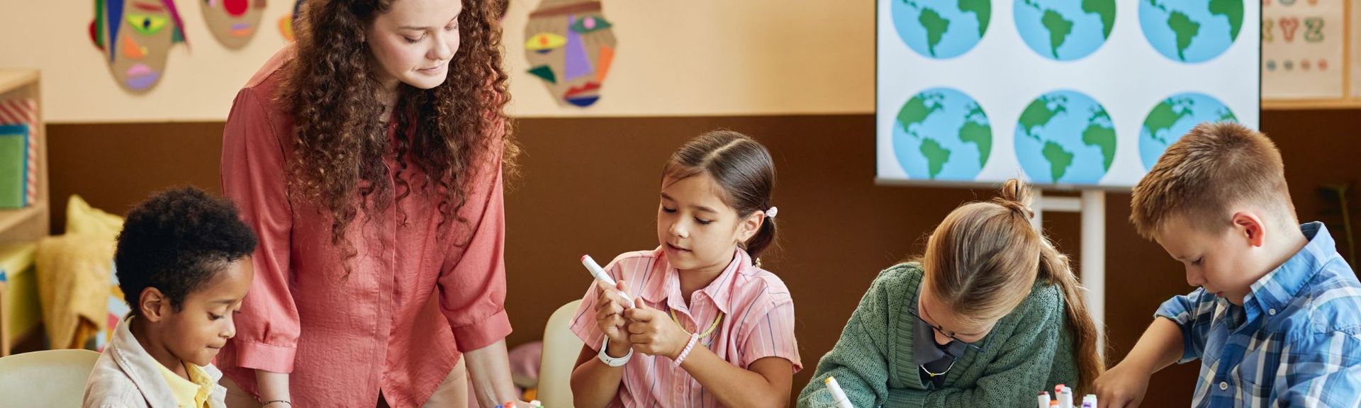 A group of four international pre-schoolers working on a class project along with their teacher in an after-school english club around Zurich, Switzerland.