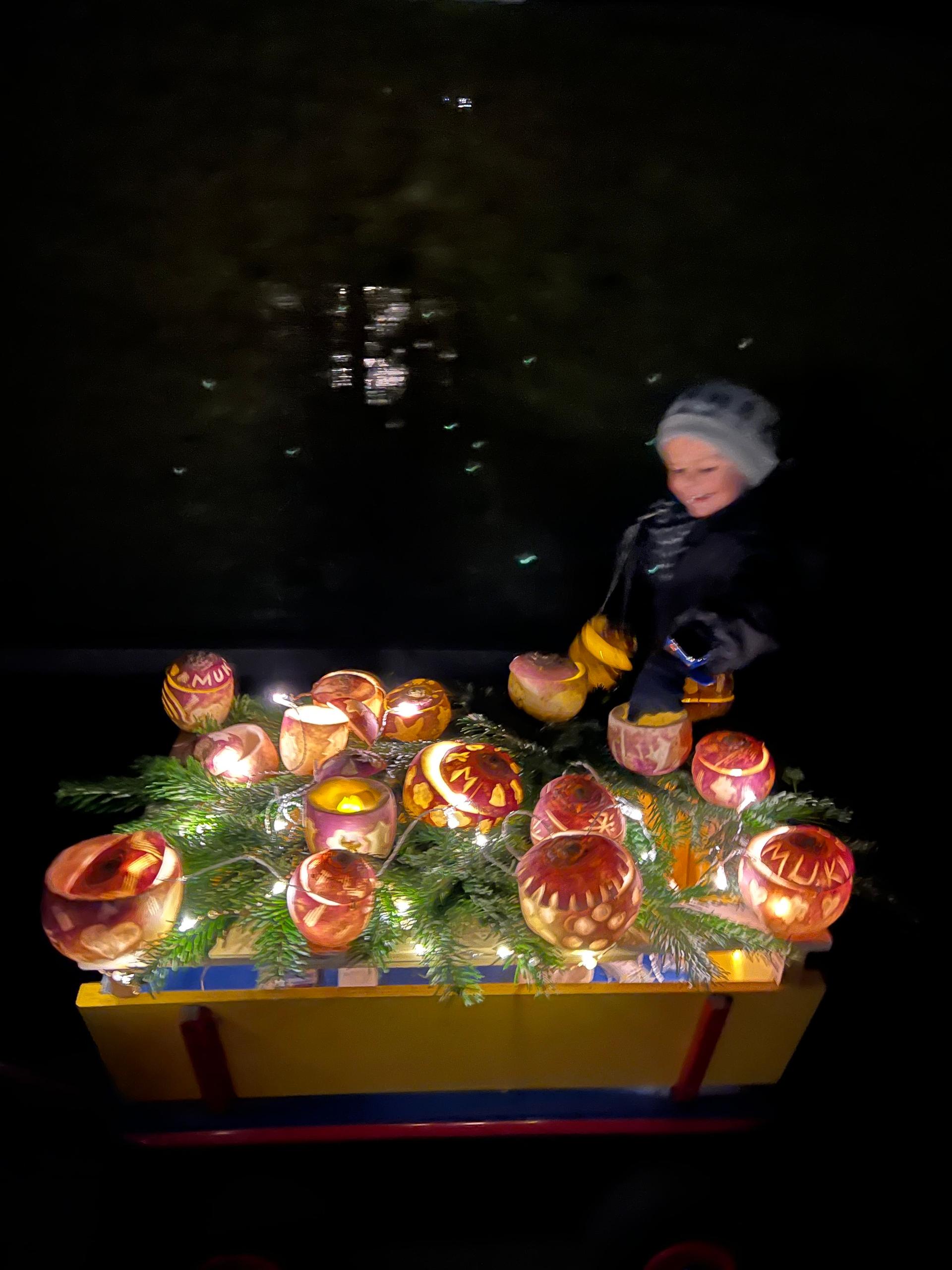 A child dressed-up in warm clothes and a woollen hat in the night smiles while looking at a carriage full of glowing turnip lanterns during the Räbeliechtli parade in Richterswil, Switzerland.